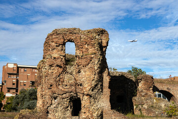 Ruins of Castello di Galliera, where old meets new, with a plane overhead in the modern landscape of Bologna, Italy