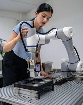 Hispanic engineer woman working on AI technology in robotics electronics engineering laboratory. University students' research project is programming robot machine with intelligent mechanical control