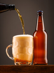 A bottle of beer and a glass of beer on a dark background.