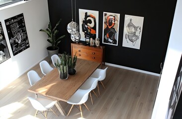 A Scandinavian-style dining room with white chairs, a wooden table, and a black wall featuring posters of abstract art.
