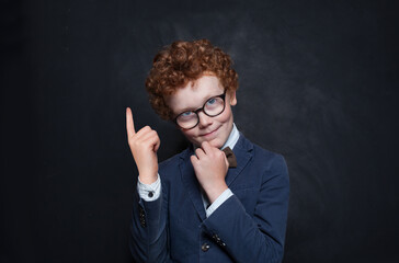 School child boy pointing finger up at copy space on black banner background