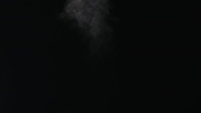 Slow motion water mist puff stream over black background