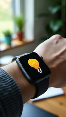 Digital watch on hand with light bulb icon, representing creativity, inspiration, and control of smart lighting systems.