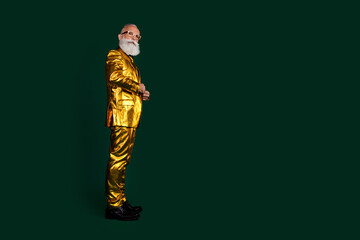 Fashionable elderly gentleman in golden suit posing with charisma against a green backdrop.