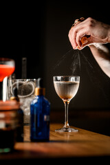 Side view of female bartender's hands squeezing a piece of zest