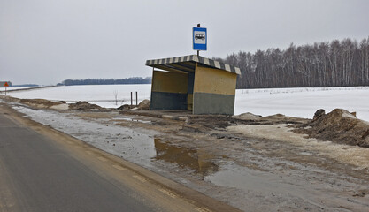 Old bus stop pavilion on a rural deserted road in winter.