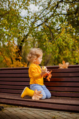 Little girl with curly hair enjoying autumn in a yellow shirt