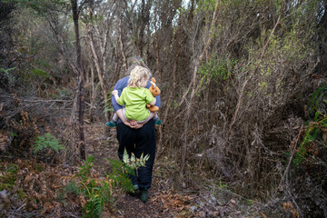Obraz premium family with a toddler and children walking in nature exploring and learning, hiking in the trees and gardens. self playing