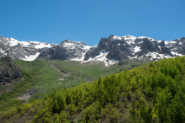 Green plains, snowy mountains. Blue sky and snowy mountains. Snowy mountains of Tunceli. Pülümür Valley, Buyer Mountain, Sarıgül Plateau, Buyer Waterfall.Munzur, Tunceli, Türkiye.
