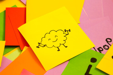 Yellow note with a drawing of a brain lifting weights on a background of multicolored notes,...