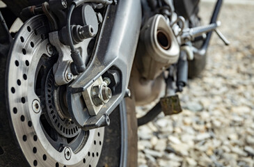 The rear of a motorcycle with chain drive to the rear wheel.