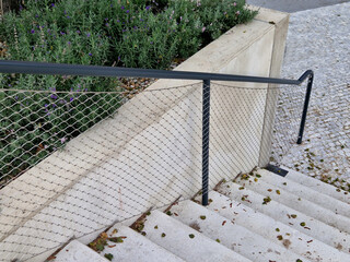 a wide staircase divided by a raised bed made of cast concrete. The handrail has handles made of...