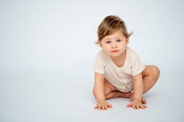 A baby boy crawls on a white isolated background with a place for text in light clothes. A small happy child, space for text