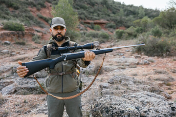 Fototapeta premium Hunter showing his rifle in nature during hunt