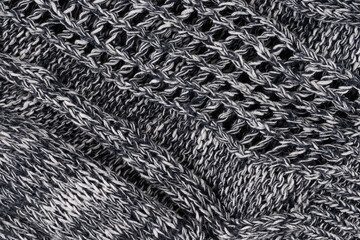 Background of gray knitted dense with white and black threads. Part of knitted sweater.