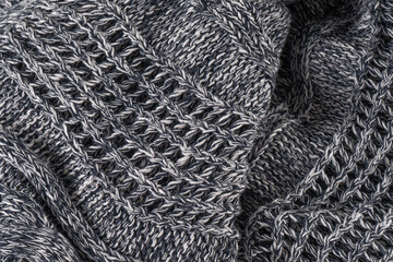 Background of gray knitted dense with white and black threads. Part of knitted sweater.