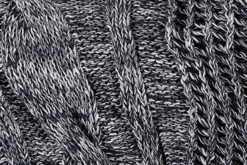 Background of gray knitted dense with white and black threads. Part of knitted sweater.