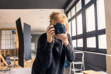 Photographer taking photos in professional studio with lighting equipment