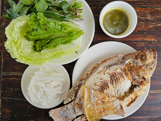 salt crusted grilled Red Tilapia fish and vegetable, Thai Rice Noodles, spicy dipping sauce on a...