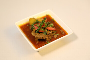 Tender pieces of beef curry with colorful chunks of potato and bell peppers. Decorated with red chili and garnished with fresh coriander leaves.