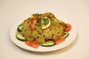 Bowl of flavorful green rice, garnished with fresh herbs and tangy lemon slices. arrange colorful slices of cucumber and ripe tomatoes around the rice.