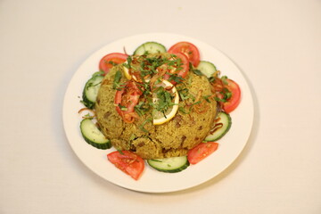 Bowl of flavorful green rice, garnished with fresh herbs and tangy lemon slices. arrange colorful slices of cucumber and ripe tomatoes around the rice.