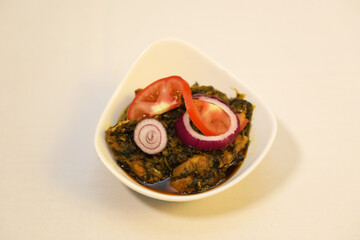 Home-made fish curry garnished with slices of red onions and fresh tomato.