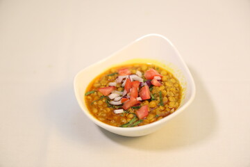 Deshi chotpoti garnished with fresh diced tomatoes, onions, and a sprinkle of green herbs.