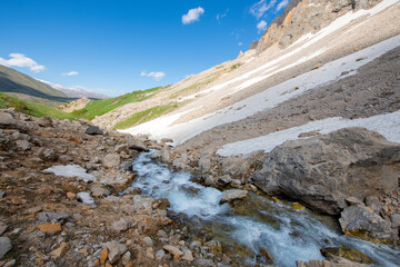Long exposure river, stream. Glacial valleys and streams. Blue sky and snowy mountains. Snowy mountains of Tunceli. Pülümür Valley, Buyer Mountain, Sarıgül Plateau, Buyer Waterfall. Türkiye.