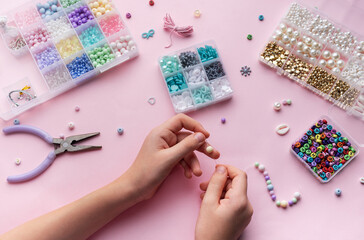 Crafting colorful jewelry with beads on a pastel workspace featuring tools and various materials