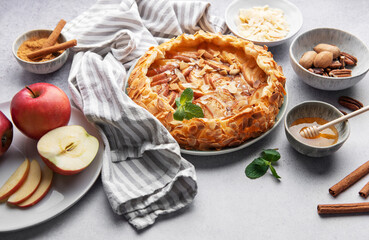 Delicious apple tart with almonds and honey served on a rustic table with fresh apples and spices