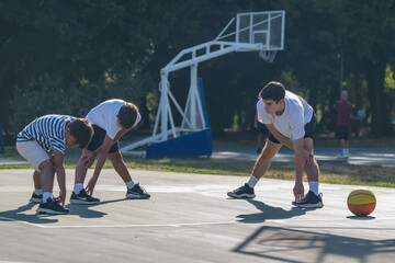 Boys stretches with a coach during basketball training, focusing on flexibility and sports fundamentals. Active coaching and essential warm up for youth basketball players.