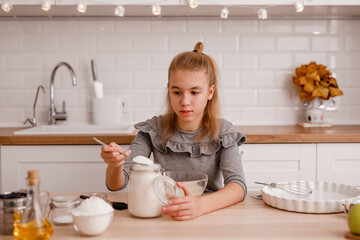 Attractive teenager girl is cooking on kitchen. Having fun while making cakes and cookies.