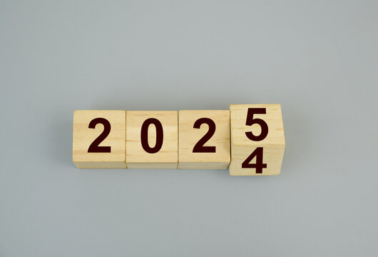 Wooden cubes with numbers changing 2024 and 2025 on gray background. Flipping of 2024 to 2025.
