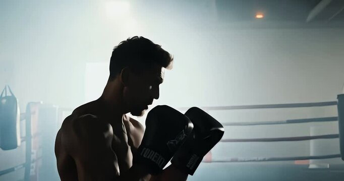 Young male boxer in silhouette during a training session, focused and determined