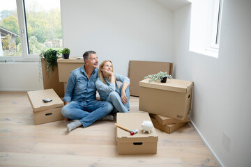 middle-aged couple sitting on the floor in their new apartment, surrounded by moving boxes