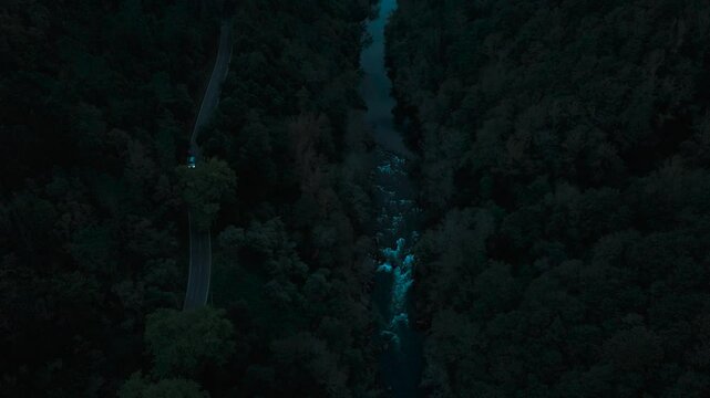 parallel road with cars and river stream dark drone view