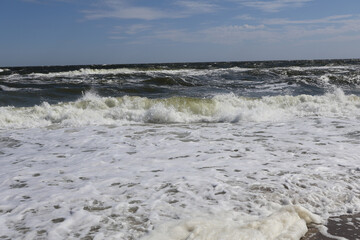 Powerful Ocean Waves Crashing on Sandy Shoreline with Sea Foam