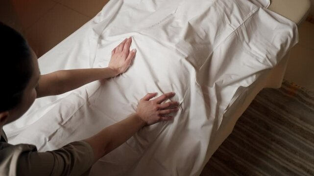 close up in massage parlor on a massage stand a girl is covered with a white cloth dry rubbing preliminary warming up of the hands of the masseur