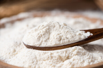 close up of wheat flour in wooden spoon on table