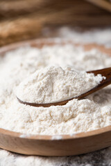 close up of wheat flour in wooden spoon on table
