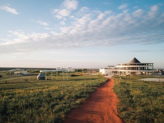 A vast, open landscape with a red dirt pathway leading through it