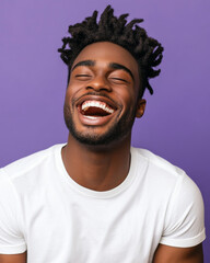 A young man laughing joyfully, dressed casually, set against a pastel purple background.