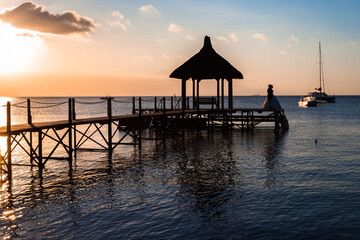 Couple romantique sur ponton mauricien au coucher du soleil 