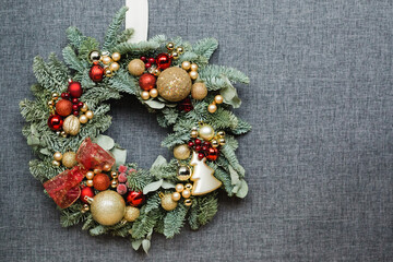 Christmas wreath decorated in gold and red colors on a gray background