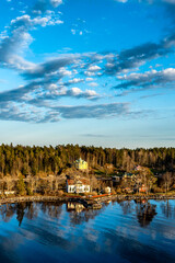 Small idyllic port in the Swedish archipelago outside of Stockholm with beautiful reflection lighted with sunspot at autumn evening.