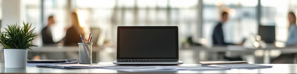 Modern office desk with laptop, papers, and plant
