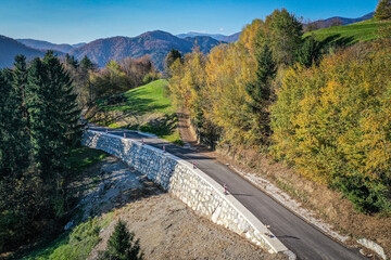 Concrete and Stone Support Wall for Asphalt Road with Scenic View of Nature, Blue Sky, and Hills