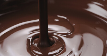 closeup pouring melted dark chocolate from spoon