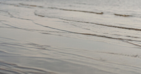 closeup of small waves on a beach at sunset